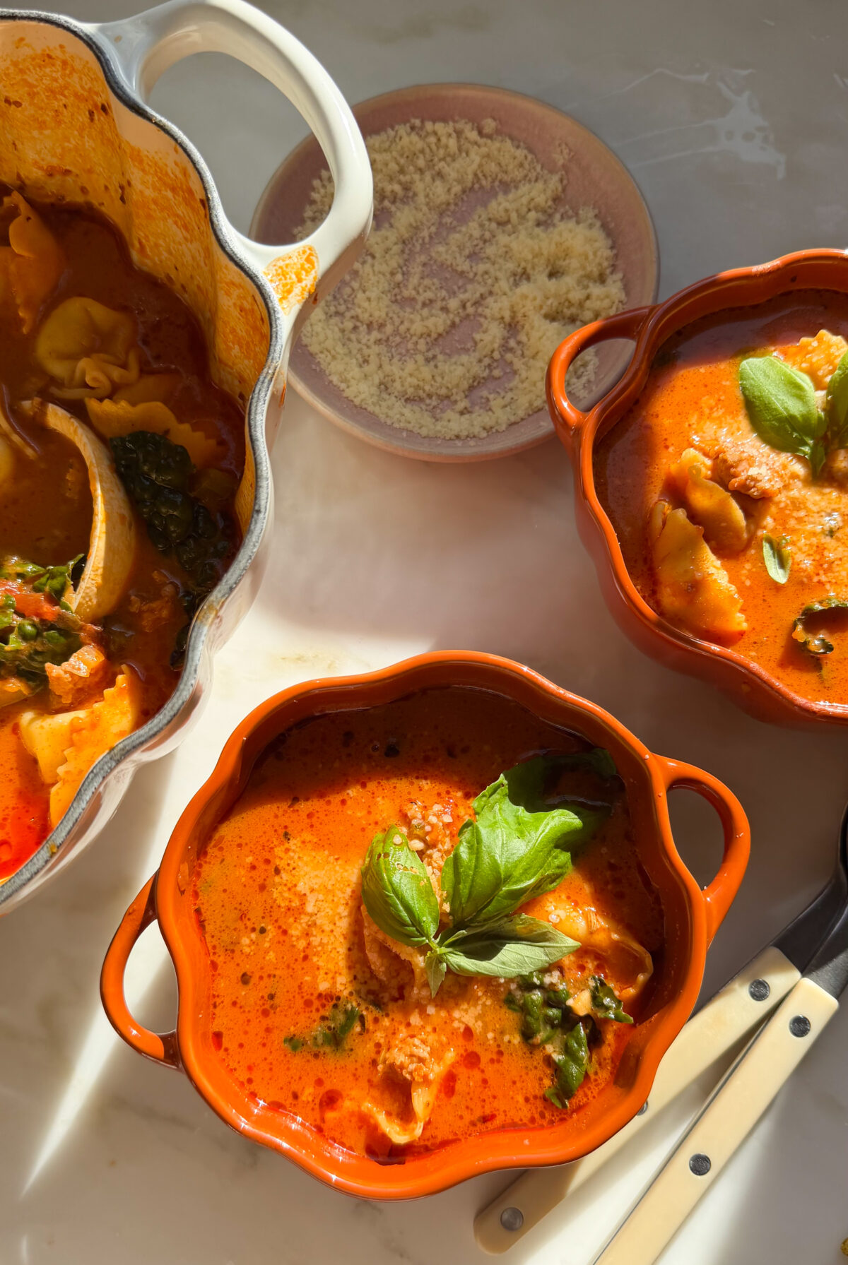 Bowls of tortellini soup with a fresh basil garnish.