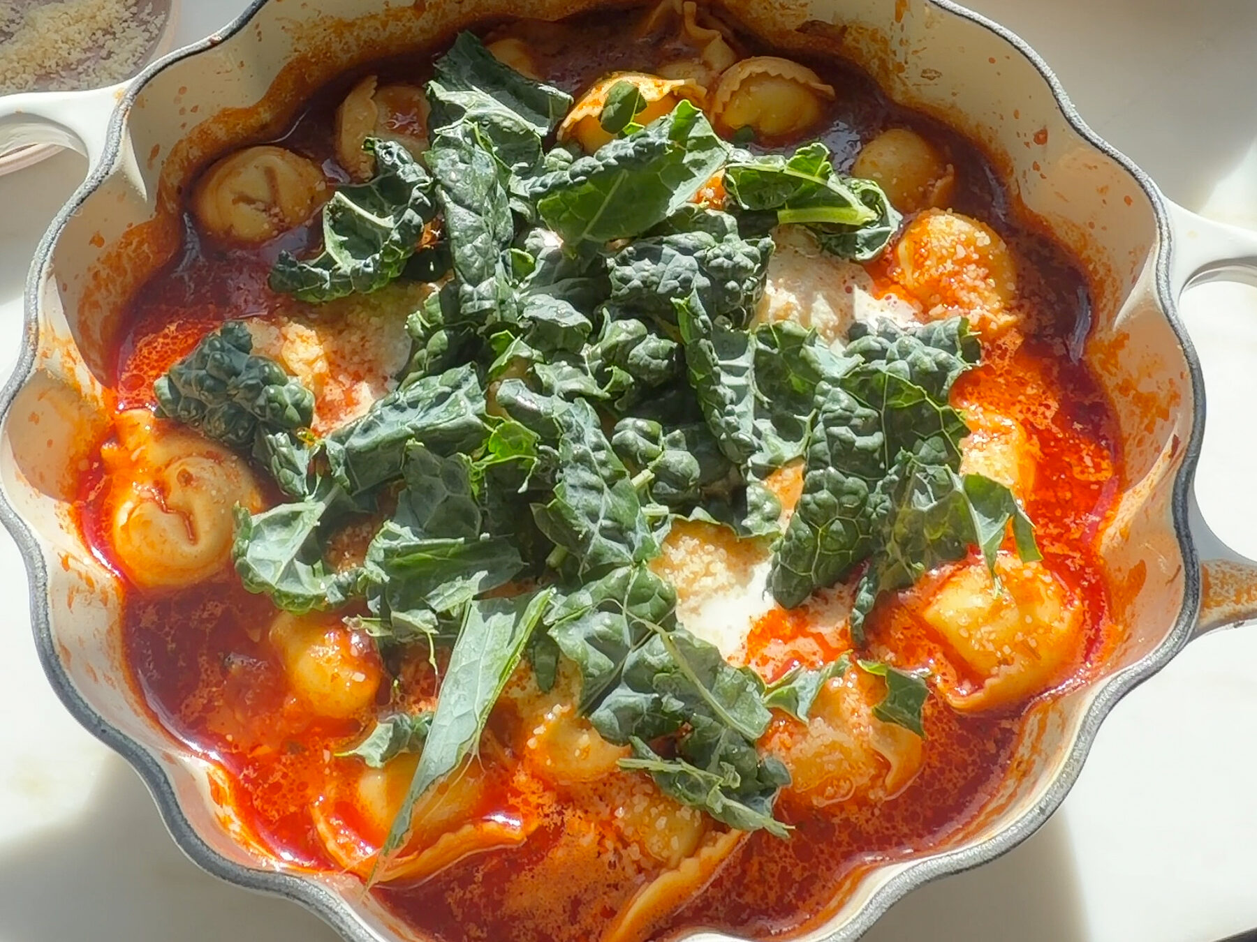 Pot of tortellini soup with a mound of kale on top.