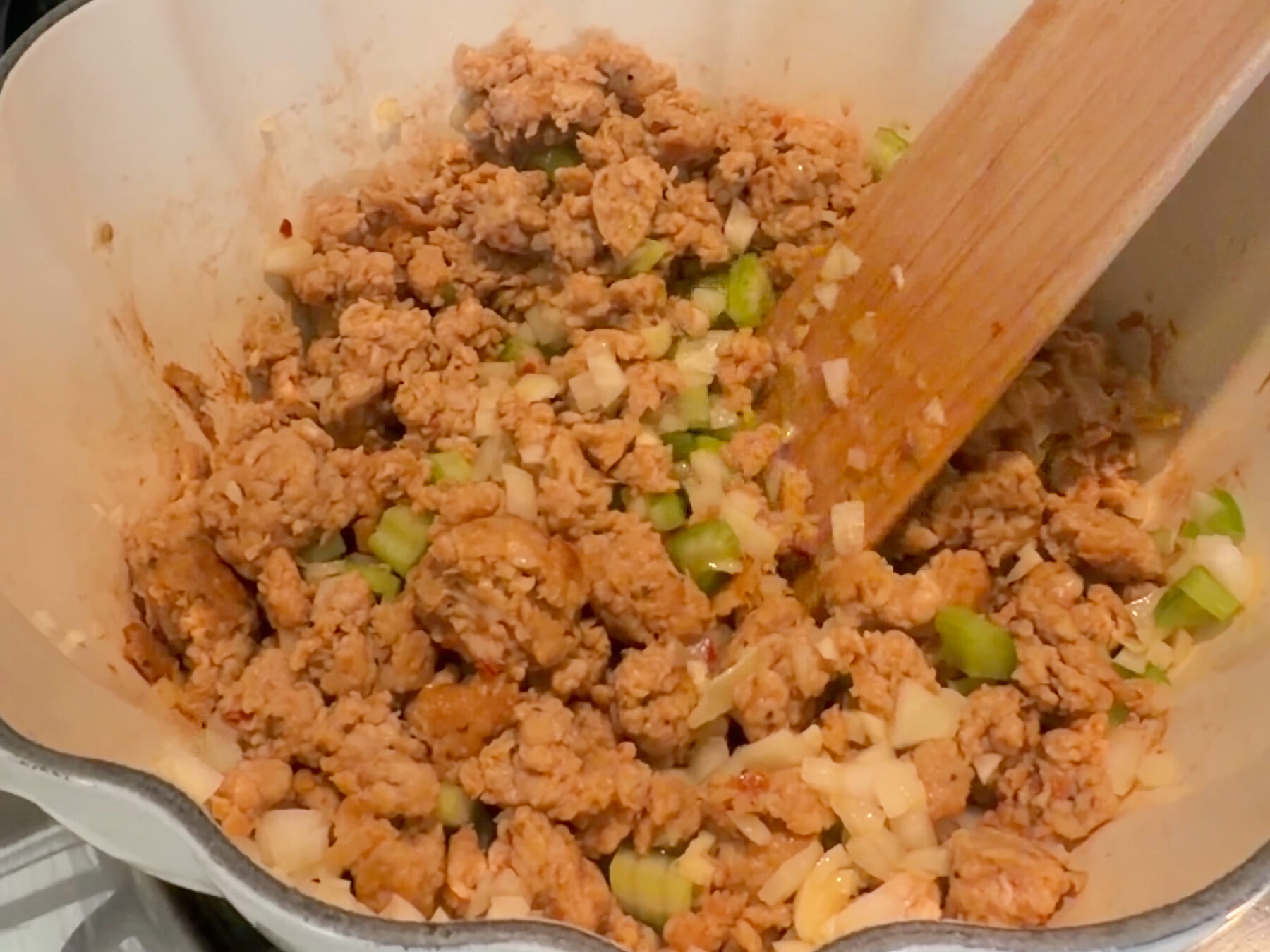Browned sausage sauteing with yellow onion and celery.